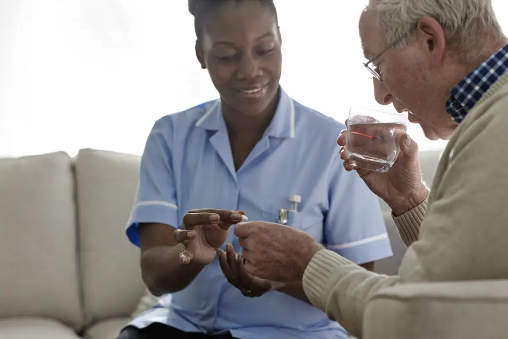 female-nurse-helping-senior-man-with-medication-at-home