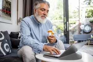 senior-holding-prescriptions-on-computer