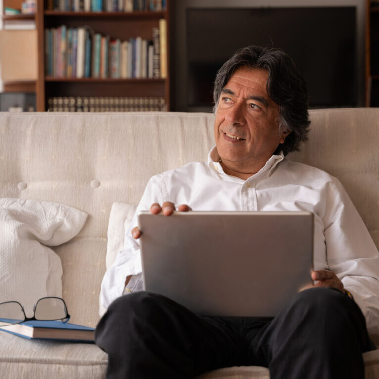 man-sitting-on-cream-couch-with-laptop