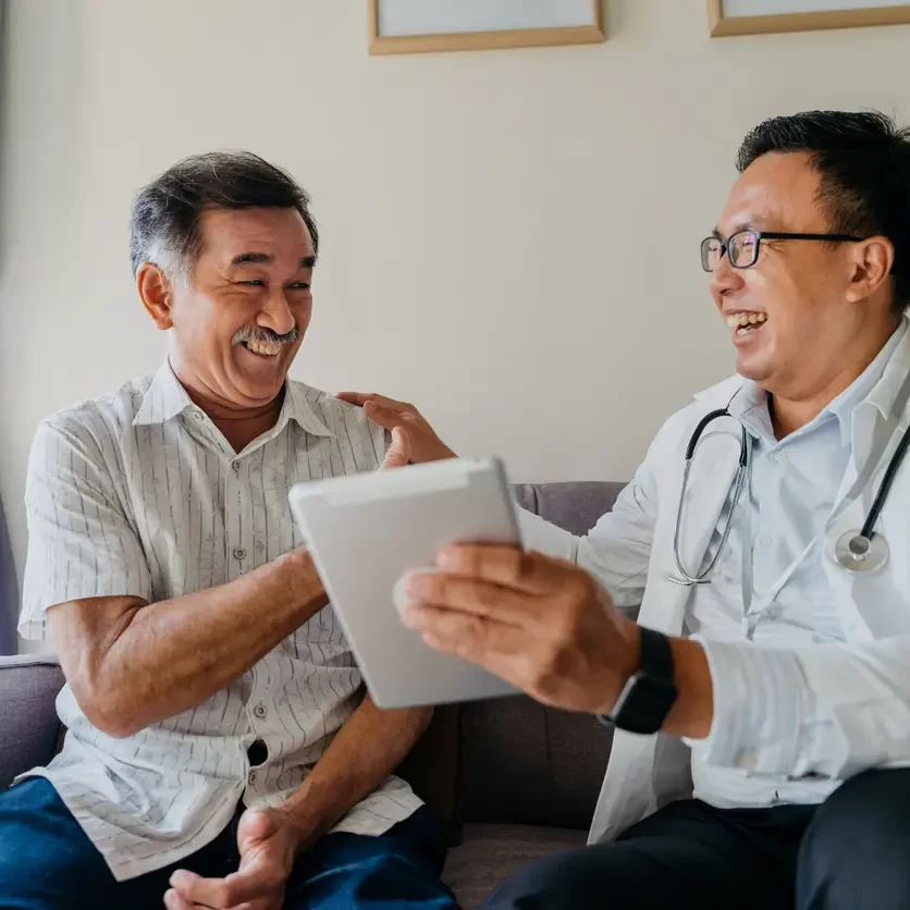 senior-laughing-with-doctor-holding-tablet