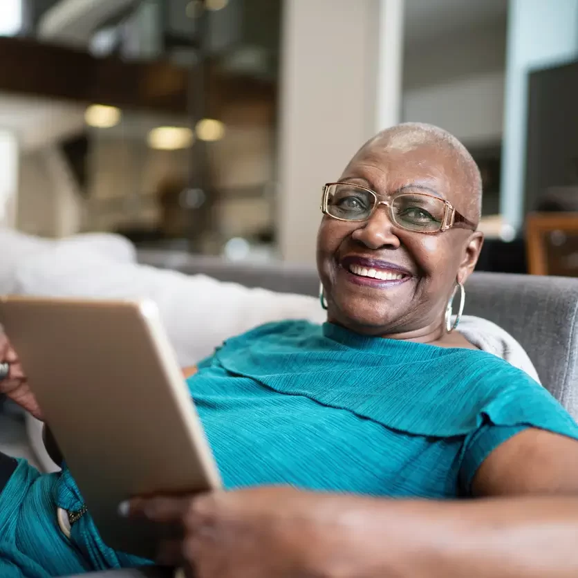 senior-woman-in-blue-shirt-holding-tablet-smile